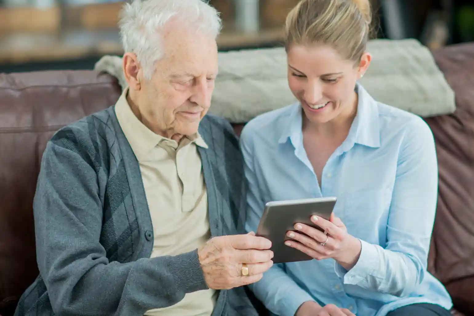 A young guide helping a senior man with a tablet